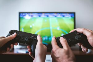 Two People Holding Black Gaming Consoles