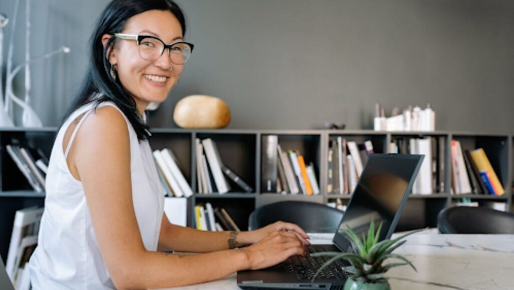 Woman Using a Laptop and Smiling at the Camera