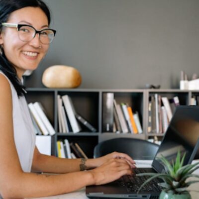Woman Using a Laptop and Smiling at the Camera