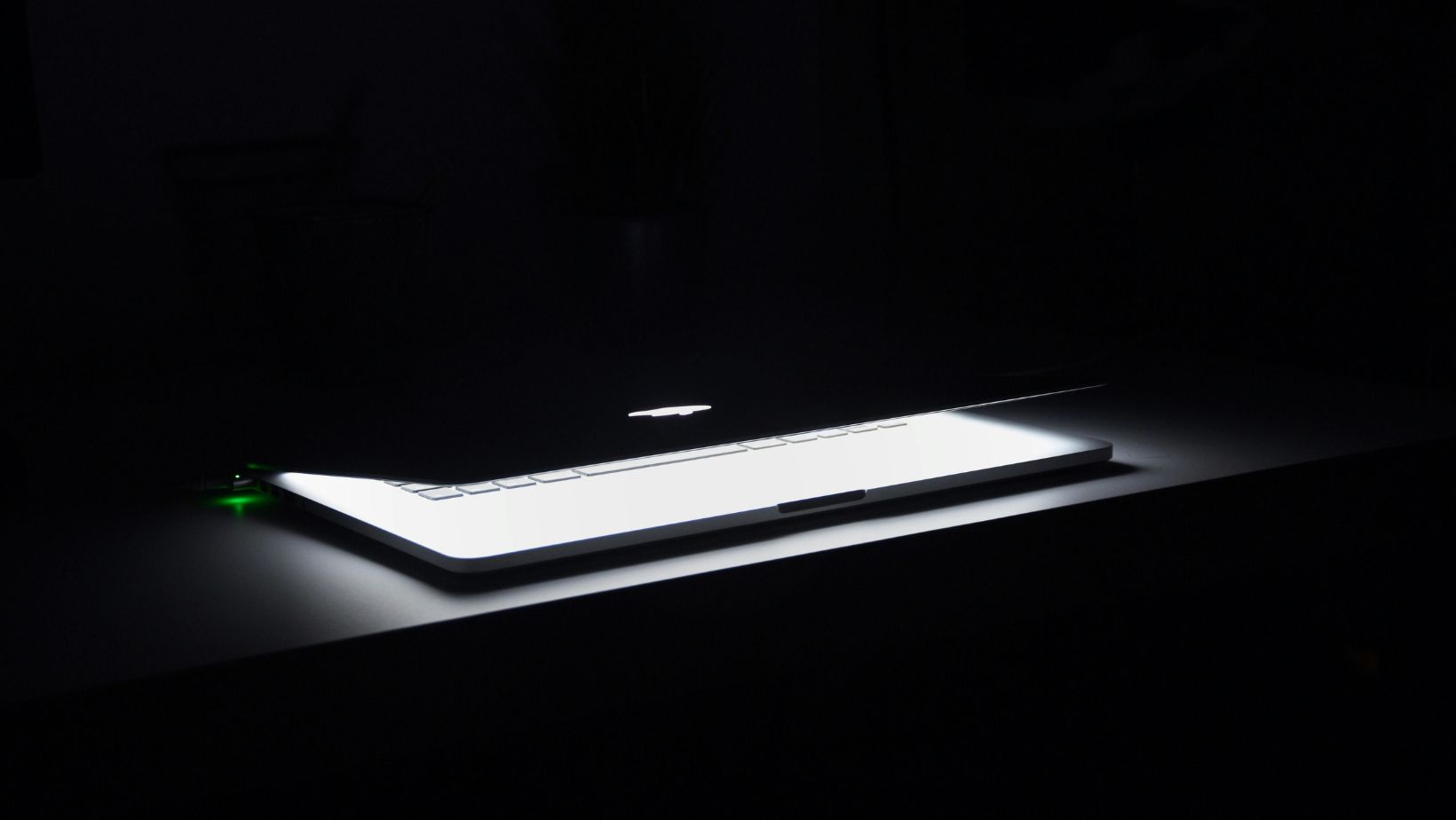 Macbook Half Opened on White Wooden Surface.